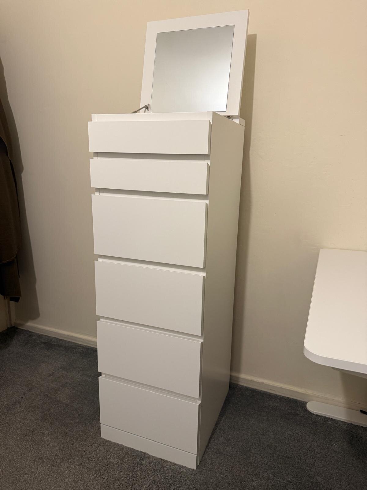 Tall white IKEA chest of drawers with a flip-up mirror lid, assembled in a London bedroom